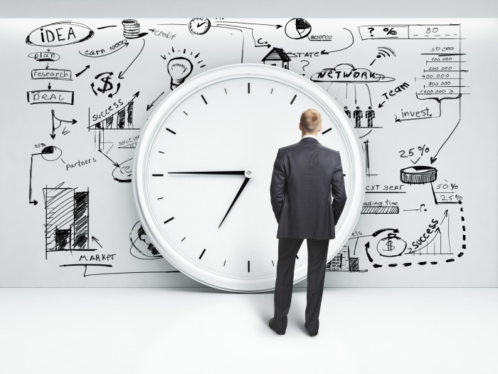 man looking at clock and business strategy on a wall